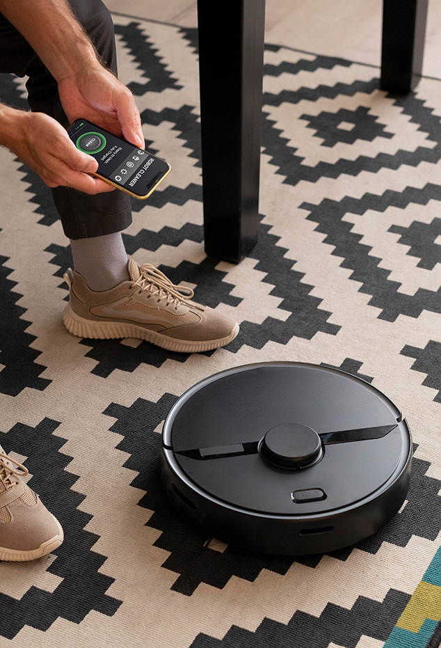 man-controlling-robot-vacuum-with-his-phone